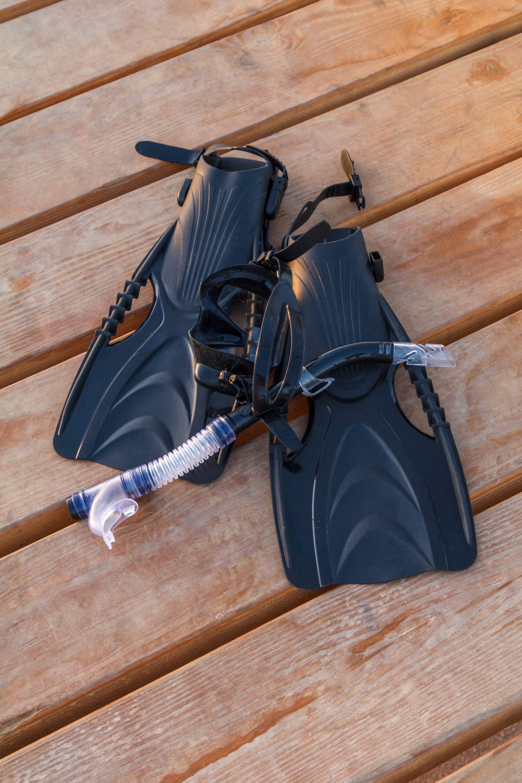 Swimming fins, dive mask and snorkel for professionals on wooden pier. a-diving-equipment-with-regulators-and-tools-for-checking-barrels.